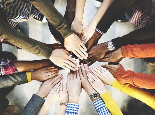 A diverse group placing their hands together