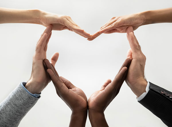 A diverse group of hands forming a heart shape together